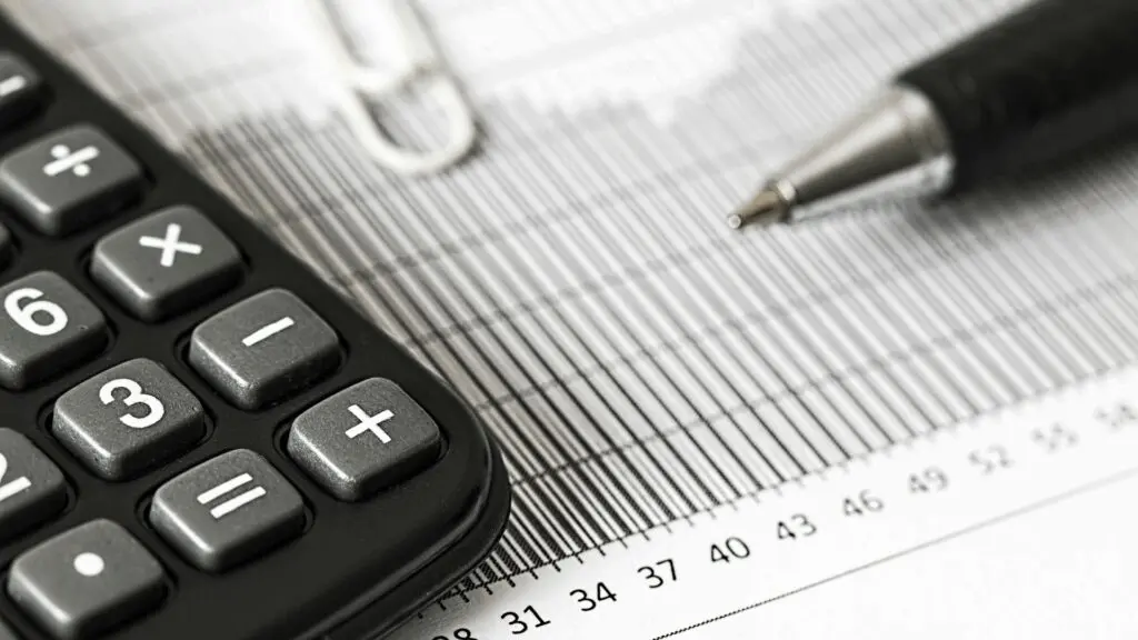 A close-up of a calculator and pen resting on a financial bar chart or tax document.